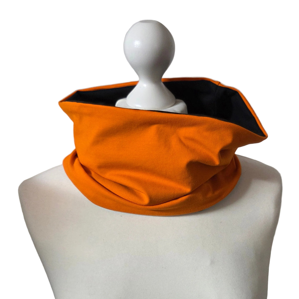 An orange athletic neck gaiter with a black interior lining, displayed on a white mannequin torso against a plain white background.