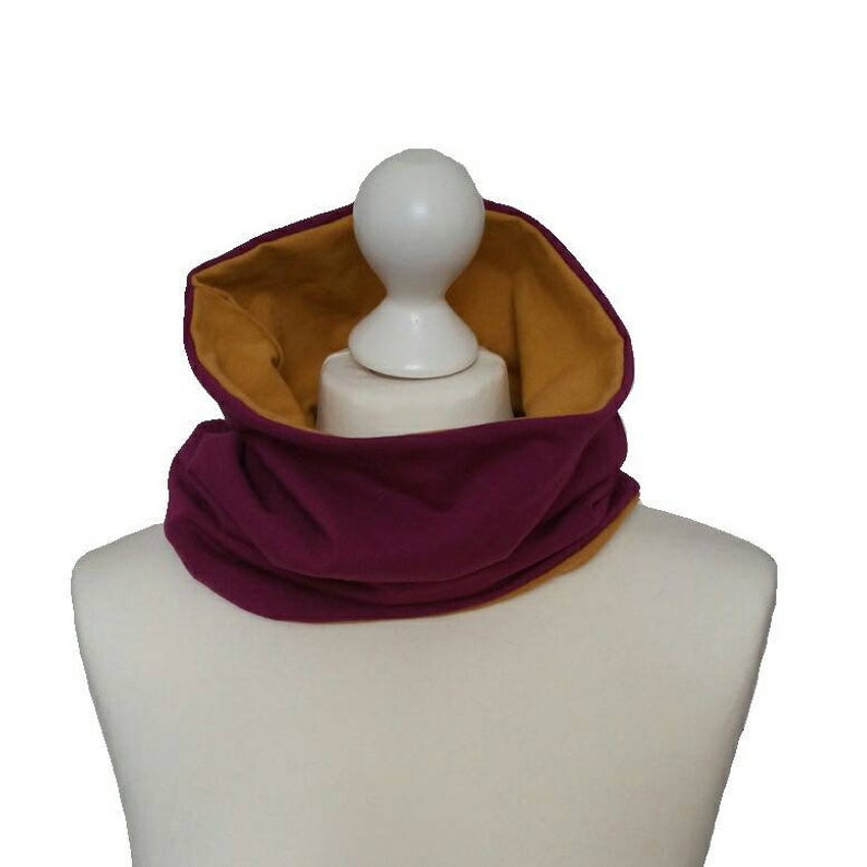 Mannequin wearing a burgundy and mustard yellow scarf on a white background