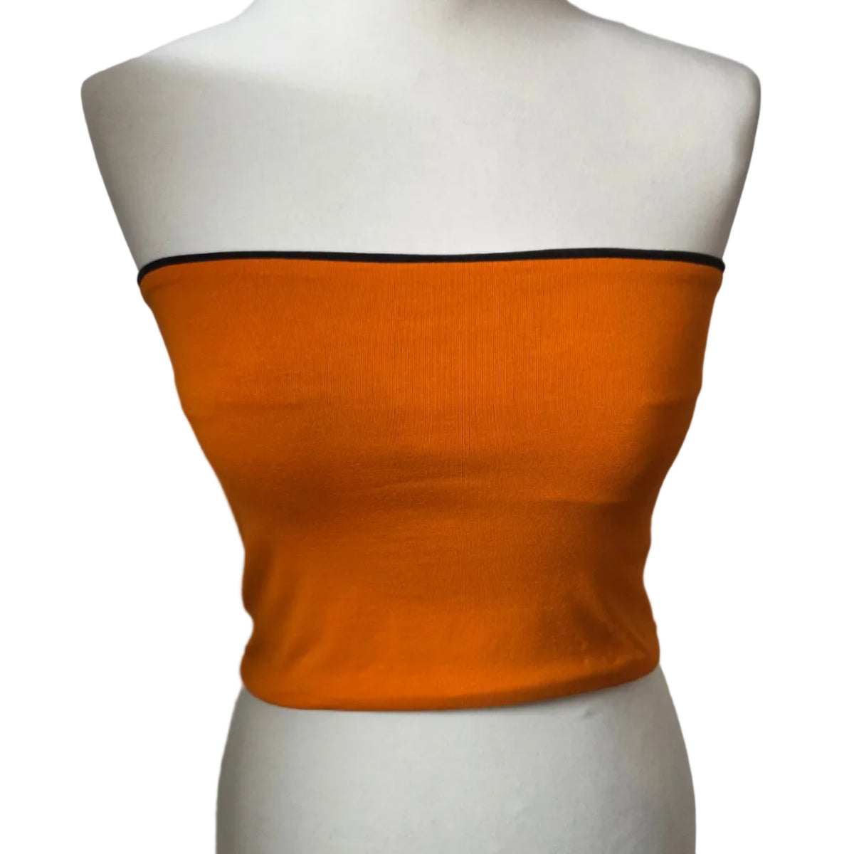 Bright orange strapless bandeau top displayed on a white mannequin torso against a white brick wall background.