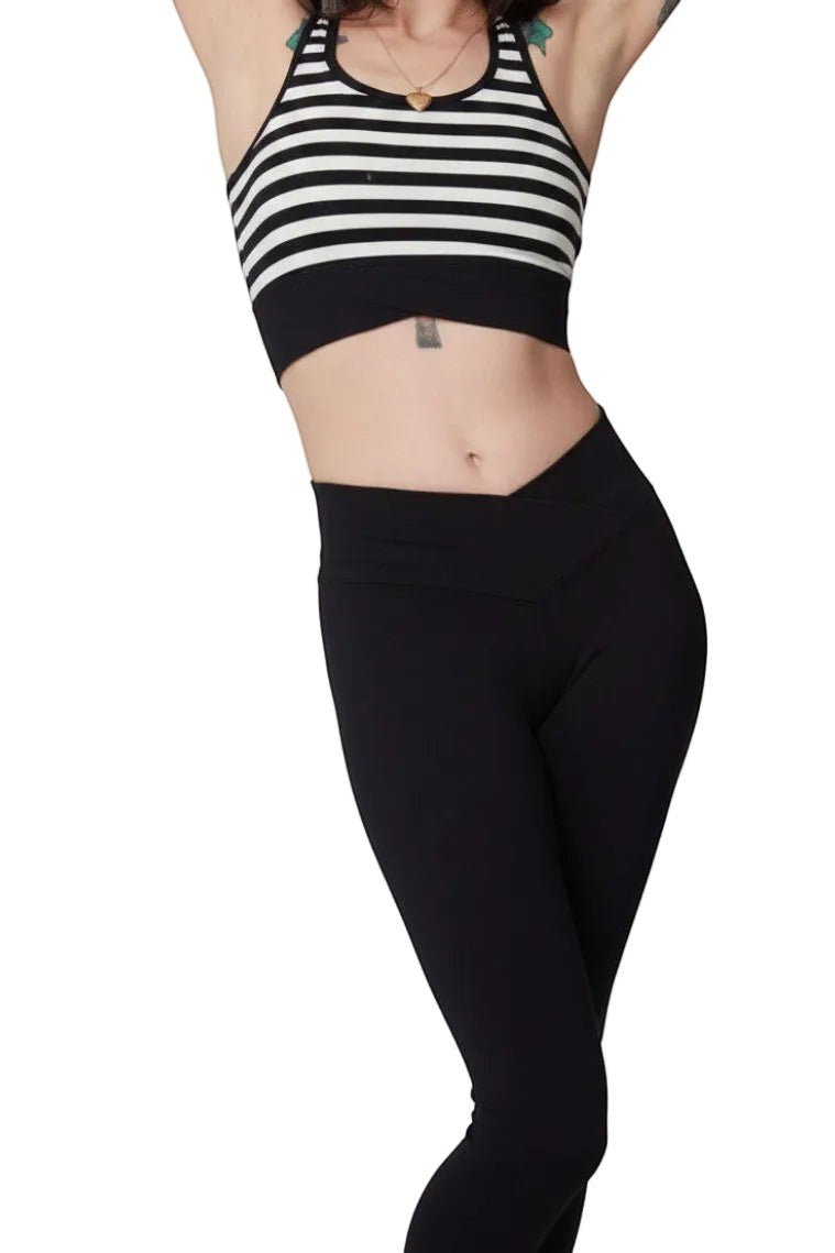 Fly and Fit black cotton leggings with a flattering V-shape waistline worn by a person in a striped crop top