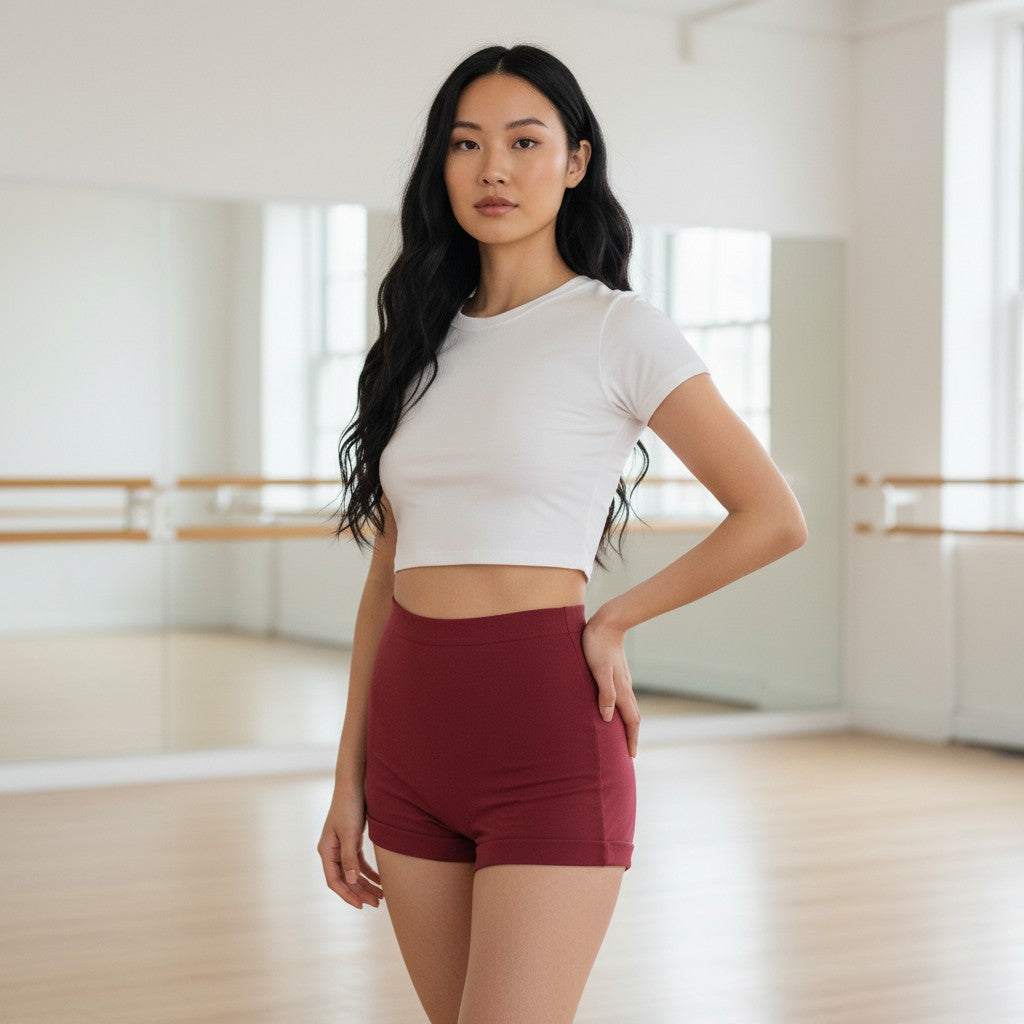 Model wearing Fly and Fit high-waist maroon cotton movement shorts in a bright dance studio.