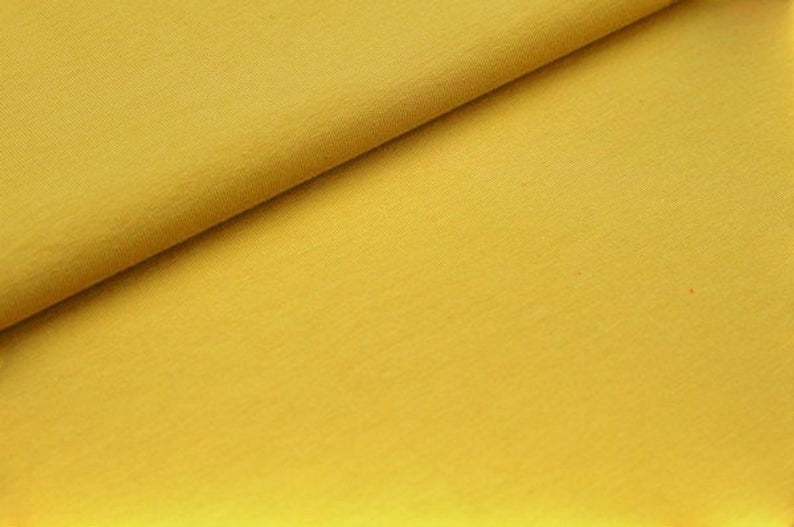 Close-up of Fly and Fit reversible core warmer fabric in vibrant mustard yellow cotton blend for yoga and dance