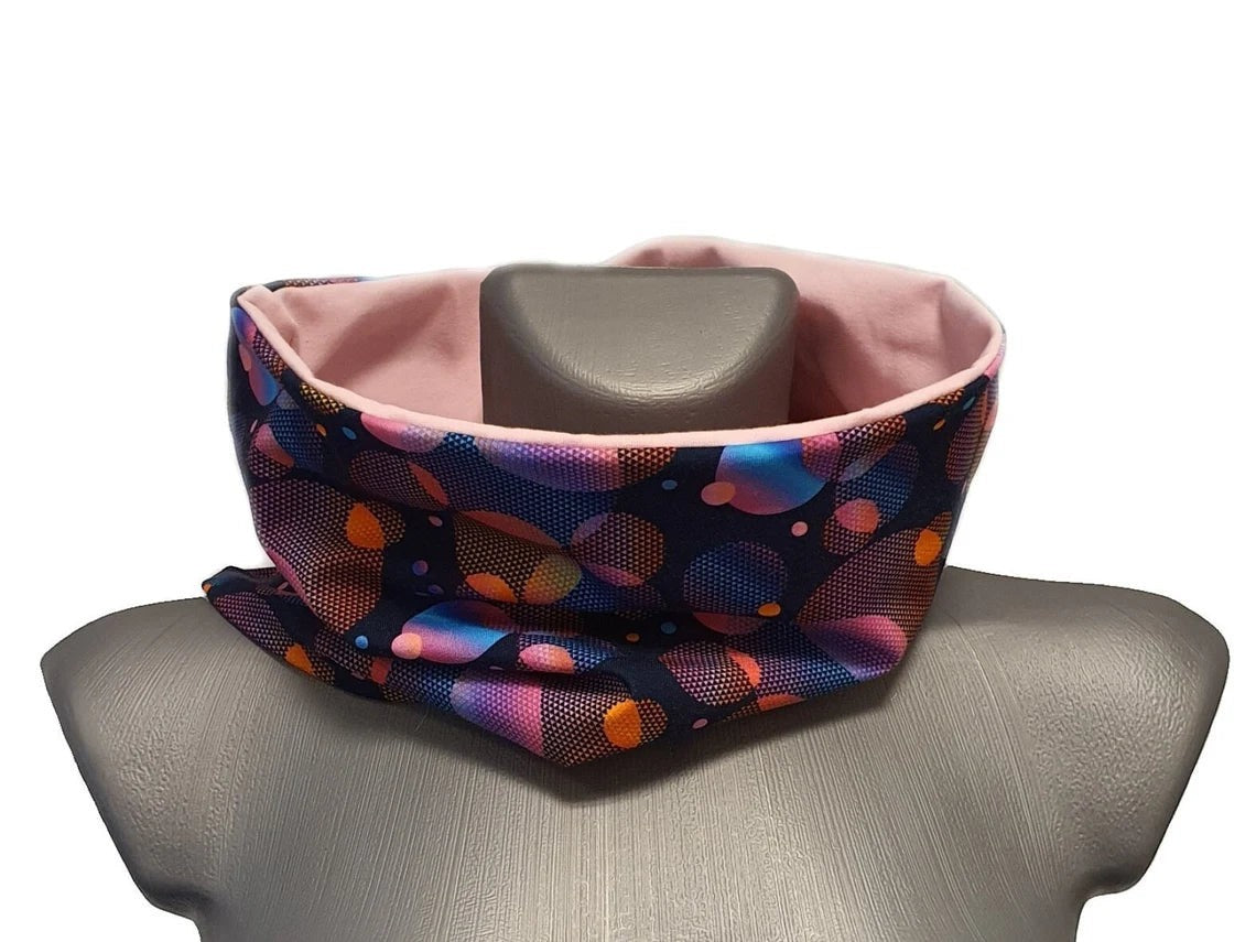 Fly and Fit reversible cotton jersey back warmer with a colorful bubbles print on one side and solid pink on the other.